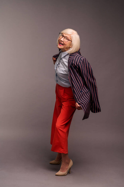 Loira seniores mulher elegante em calças vermelhas e casaco elegante - Foto, Imagem