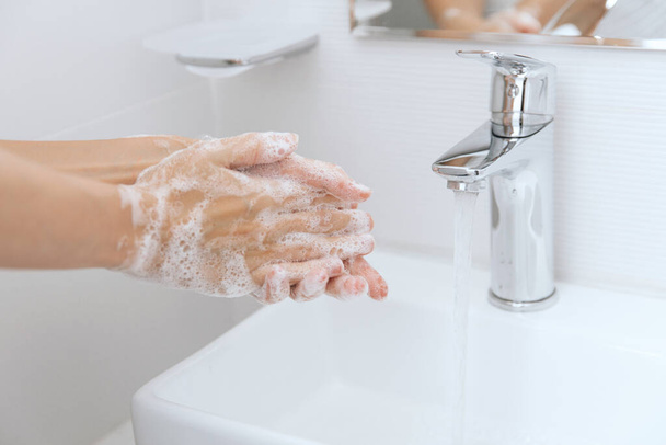 Washing hands under the flowing water tap. Washing hands rubbing with soap for corona virus prevention, hygiene to stop spreading corona virus in or public wash room. Hygiene concept hand detail - Photo, image