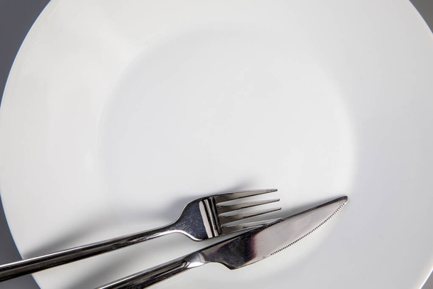 Empty plate with fork and knife on gray background, top view for copy space, food and healthy eating concept space for text - Zdjęcie, obraz