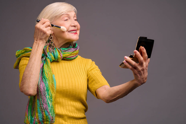 Kortharige blonde senior vrouw doet make-ip - Foto, afbeelding