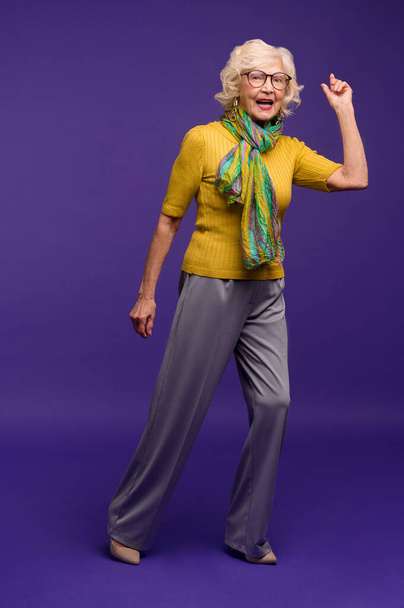 Senior woman in yellow shirt and with a green scarf feeling energized - Photo, Image