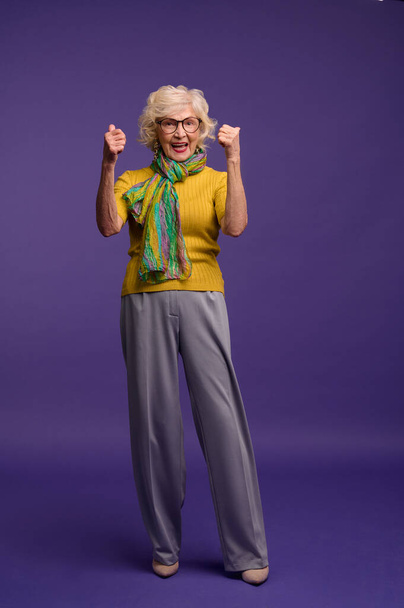 Senior vrouw in geel shirt en met een groene sjaal gevoel energiek - Foto, afbeelding