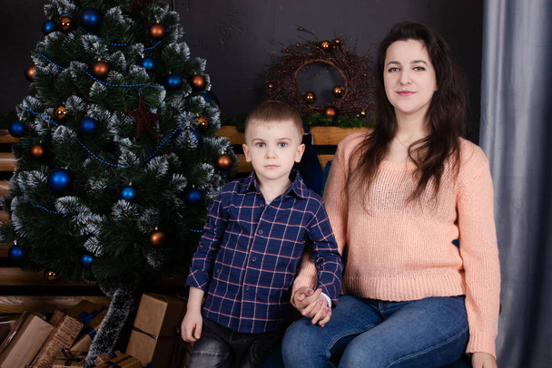 little toddler boy with woman near christmas tree and decoration. son and mother on christmas eve. new year. single mother. incomplete family - Fotografie, Obrázek