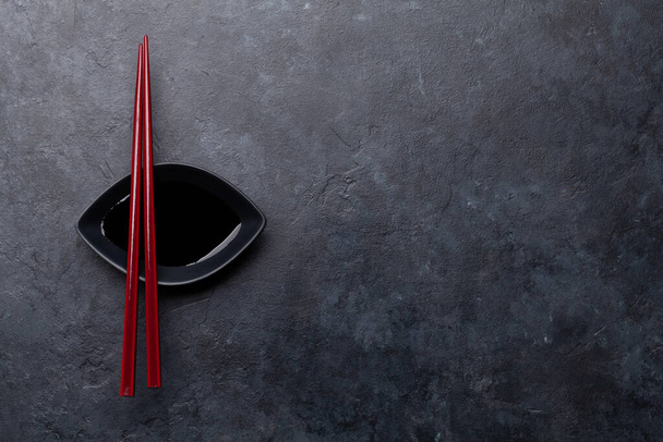 Πέτρινο τραπέζι και ξυλάκια για σούσι και μάκι. Ιαπωνικό μενού φαγητού. Πάνω όψη επίπεδη θέσει με αντίγραφο χώρου - Φωτογραφία, εικόνα