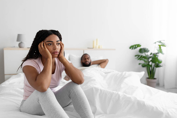 Sad young african american woman is sad and ignores her husband after scandal in comfortable bed - Zdjęcie, obraz
