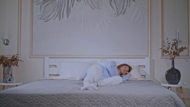 blondynka leżąca na łóżku przytomna - Materiał filmowy, wideo