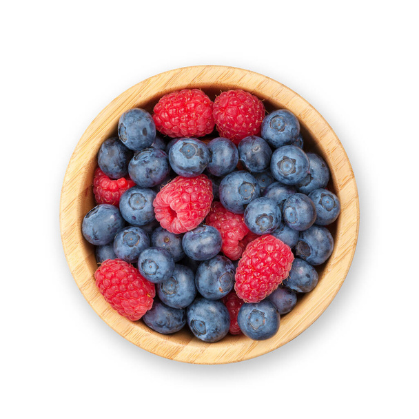 Blueberries and raspberries in wooden bowl. Isolated on white background. Top view flat lay - Fotoğraf, Görsel