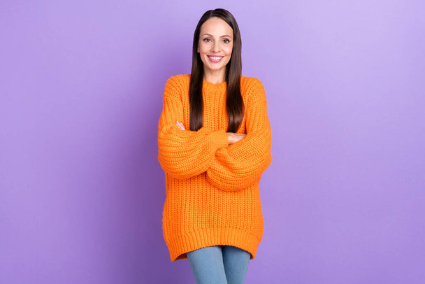 Photo of self-assured lady crossed hands shiny smile wear orange sweater isolated violet color background - 写真・画像
