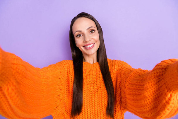 Photo of cheerful positive blogger lady take selfie beaming smile wear orange sweater isolated violet color background - 写真・画像