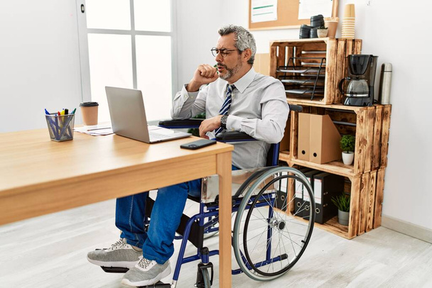 Латиноамериканец среднего возраста, работающий в офисе, сидя на инвалидной коляске, чувствует себя нездоровым и кашляет как симптом от простуды или бронхита. концепция здравоохранения.  - Фото, изображение