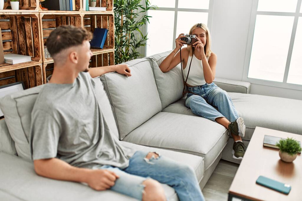 Mujer haciendo foto a su novio usando la cámara en casa. - Foto, imagen