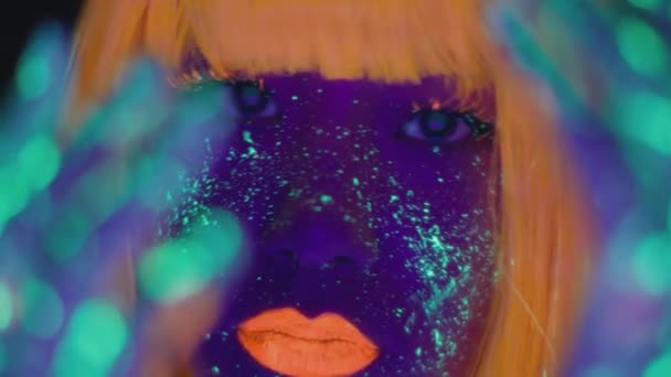 Fashion model in neon lights. Close up portrait of young asian lady with bright fluorescent makeup posing to camera - Video, Çekim