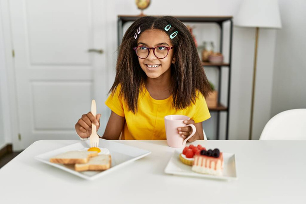 Chica afroamericana sonriendo confiada desayunando en casa - Foto, imagen