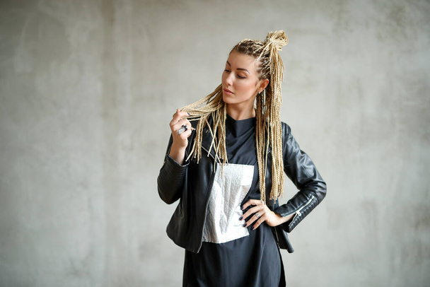 Beautiful young woman with dreadlocks posing on grey background - Foto, Imagem