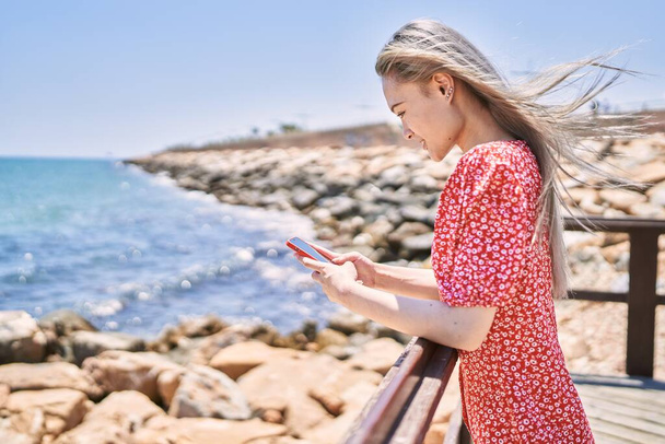 jong chinees meisje glimlachen gelukkig met behulp van smartphone op het strand. - Foto, afbeelding