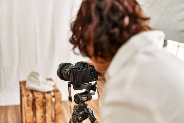 Jeune photographe hispanique femme sur la vue arrière en utilisant un appareil photo au studio photo. - Photo, image