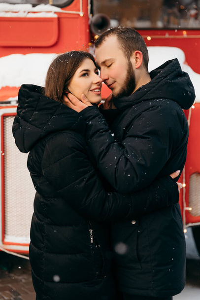 Ένα ζευγάρι αγκαλιές στο φόντο ενός κόκκινου λεωφορείου. Ημέρα του Αγίου Βαλεντίνου - Φωτογραφία, εικόνα