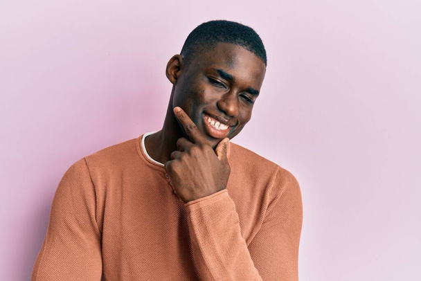 Young african american man wearing casual clothes looking confident at the camera smiling with crossed arms and hand raised on chin. thinking positive.  - Photo, Image