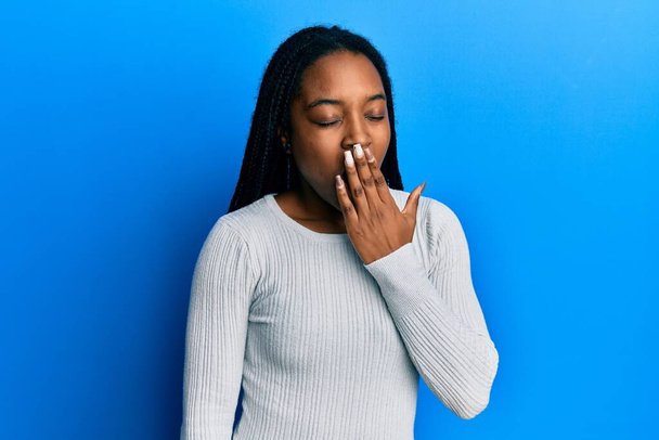 African american woman with braided hair wearing casual white sweater bored yawning tired covering mouth with hand. restless and sleepiness.  - Foto, immagini