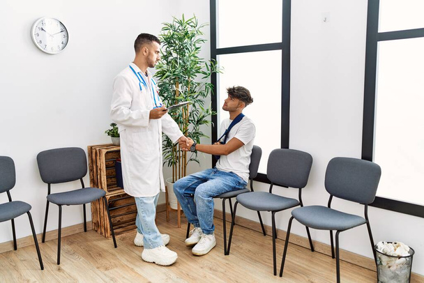 Two hispanic men doctor and patient shake hands at hospital waiting room - Photo, Image