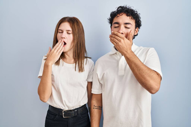Young couple wearing casual clothes standing together bored yawning tired covering mouth with hand. restless and sleepiness.  - Foto, imagen