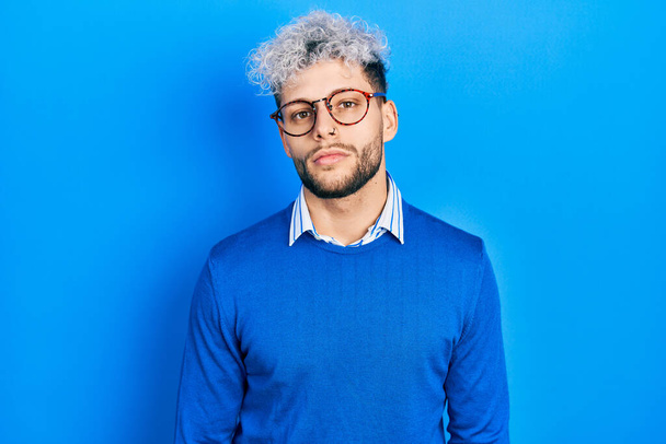 Young hispanic man with modern dyed hair wearing sweater and glasses relaxed with serious expression on face. simple and natural looking at the camera.  - Foto, Bild