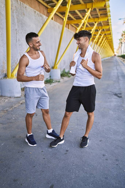 Deux hommes hispaniques couple sportif souriant confiant debout dans la rue - Photo, image