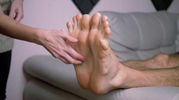 Mani femminili solletico nudo piedi maschili, dita dei piedi, disteso sul divano. Interruzione temporale - Filmati, video