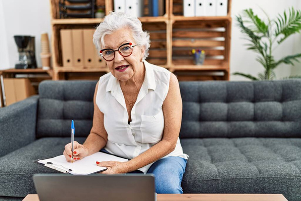 Старша сіроока жінка-психолог, що пише в буфері, використовуючи ноутбук в психологічному центрі
 - Фото, зображення
