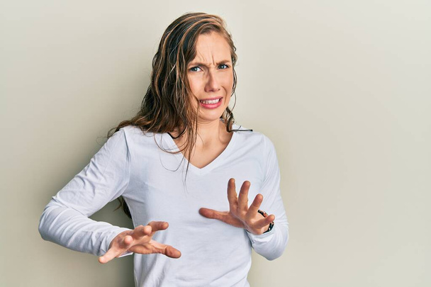 Young blonde woman wearing casual clothes disgusted expression, displeased and fearful doing disgust face because aversion reaction. with hands raised  - Photo, Image