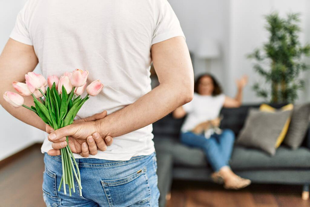 Man surprising his wife with flowers at home. - Fotografie, Obrázek
