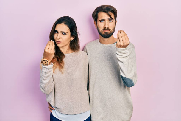 Young hispanic couple wearing casual clothes doing italian gesture with hand and fingers confident expression  - Zdjęcie, obraz