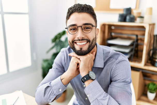 Молодой араб улыбается уверенно работая в офисе - Фото, изображение
