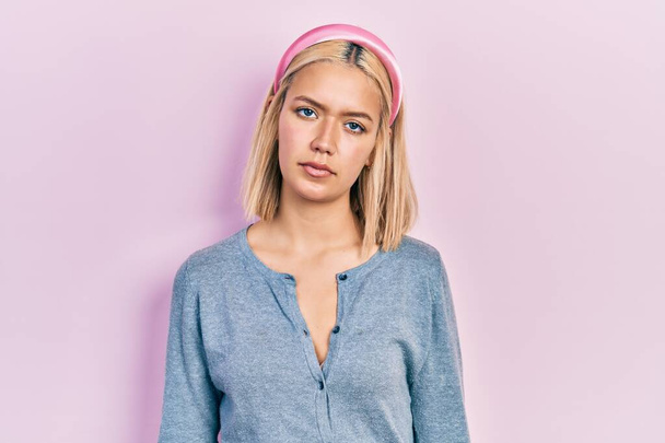 Beautiful blonde woman standing over pink background relaxed with serious expression on face. simple and natural looking at the camera.  - Foto, Bild