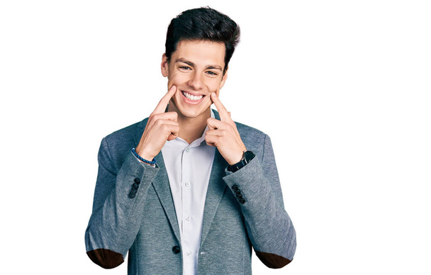 Молодой латиноамериканец в деловой одежде, улыбающийся с открытым ртом, указывающий пальцами и заставляющий веселую улыбку  - Фото, изображение