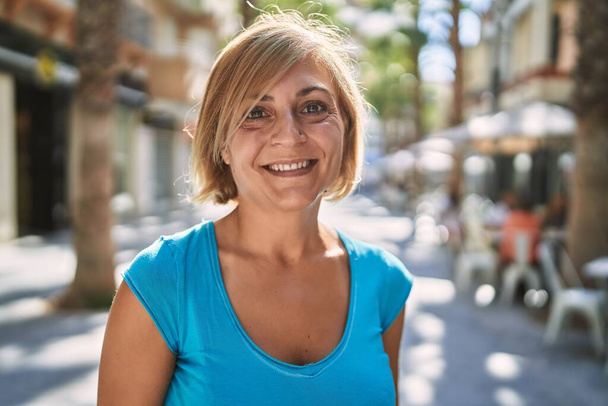 Красивая женщина средних лет, уверенно улыбающаяся на улице - Фото, изображение