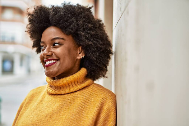 Genç Afrikalı Amerikalı kız gülümseyerek şehirde mutlu mesut duruyor.. - Fotoğraf, Görsel