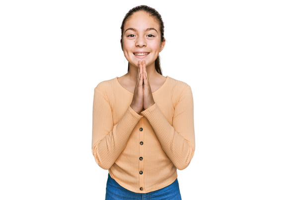 Beautiful brunette little girl wearing casual sweater praying with hands together asking for forgiveness smiling confident.  - Photo, Image