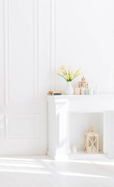 Soft home decor, white jug, vase with white and yellow beautiful flowers on a white wall background and on a wooden shelf. Interior. - Фото, зображення