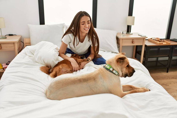 Genç İspanyol kadın yatak odasında köpeklerle oynuyor. - Fotoğraf, Görsel
