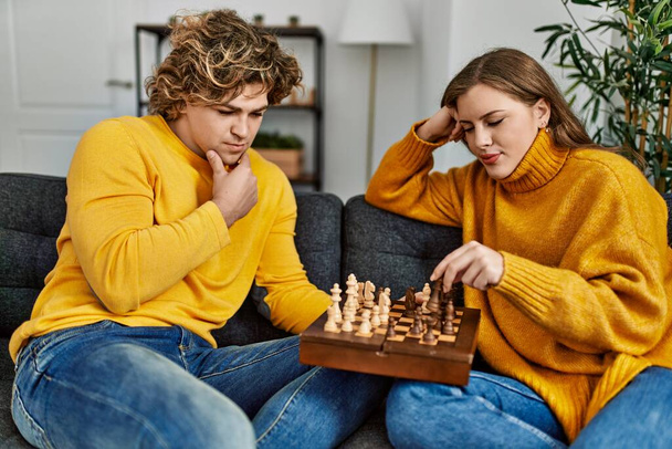 Young caucasian couple concentrate playing chess at home - Φωτογραφία, εικόνα