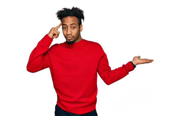 Young african american man with beard wearing casual winter sweater confused and annoyed with open palm showing copy space and pointing finger to forehead. think about it.  - Zdjęcie, obraz