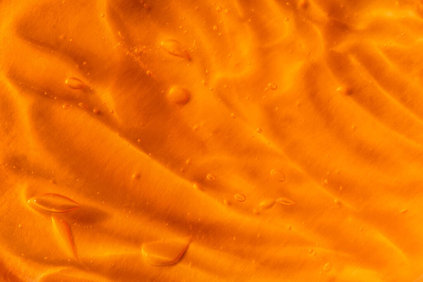Tekstuuri läpinäkyvä keltainen geeli ilmakuplia ja aaltoja oranssi tausta - Valokuva, kuva
