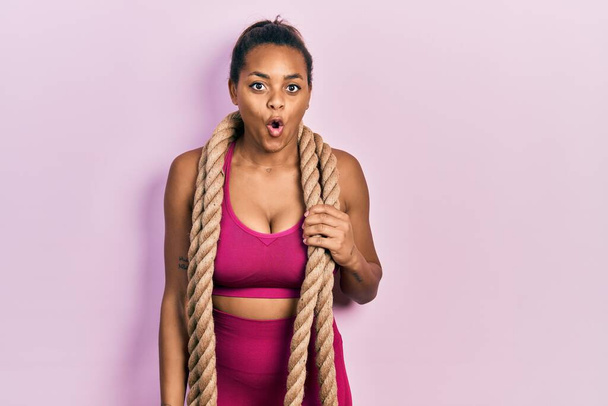 Jeune fille afro-américaine formation avec corde de combat peur et étonné avec la bouche ouverte pour la surprise, visage d'incrédulité  - Photo, image