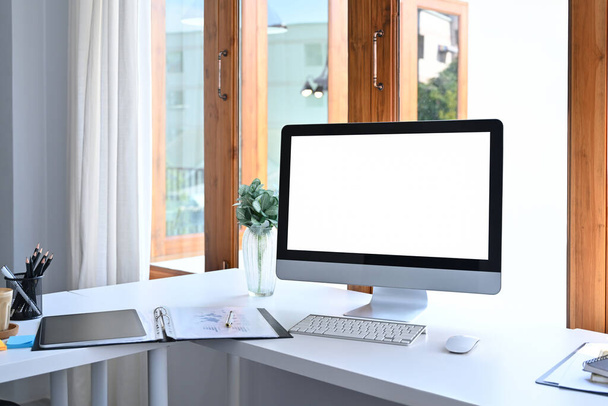 Moderno espacio de trabajo con ordenador, material de oficina y planta de interior sobre mesa blanca. - Foto, imagen