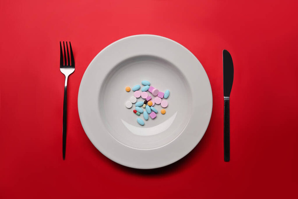 Supplements as food on round white plate with fork and knife. Concept of vitamins instead of food. - Fotoğraf, Görsel