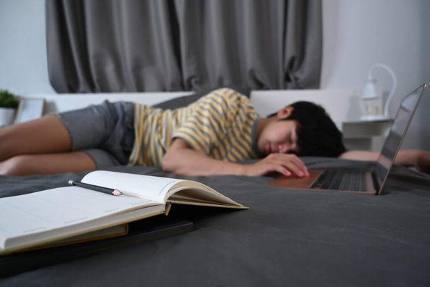Tired asian man sleeping on bed with laptop. - Foto, imagen