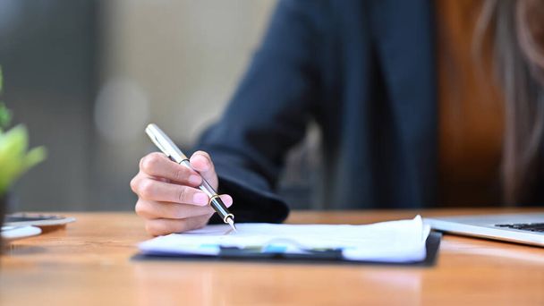 Обрезанный снимок предпринимательницы с ручкой и подпись на документе. - Фото, изображение