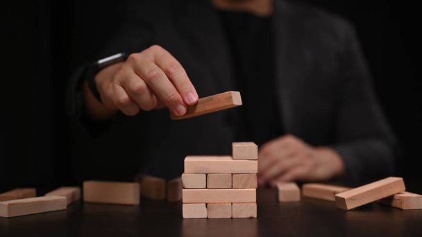 Businessman placing wooden block on a tower. Strategy and start up business concept. - Photo, Image