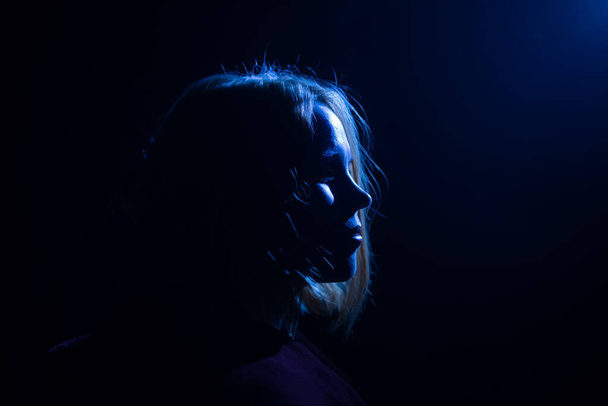Silhouette of an attractive woman portrait in blue light. Dark background. Side view. Place for your text. - Fotografie, Obrázek